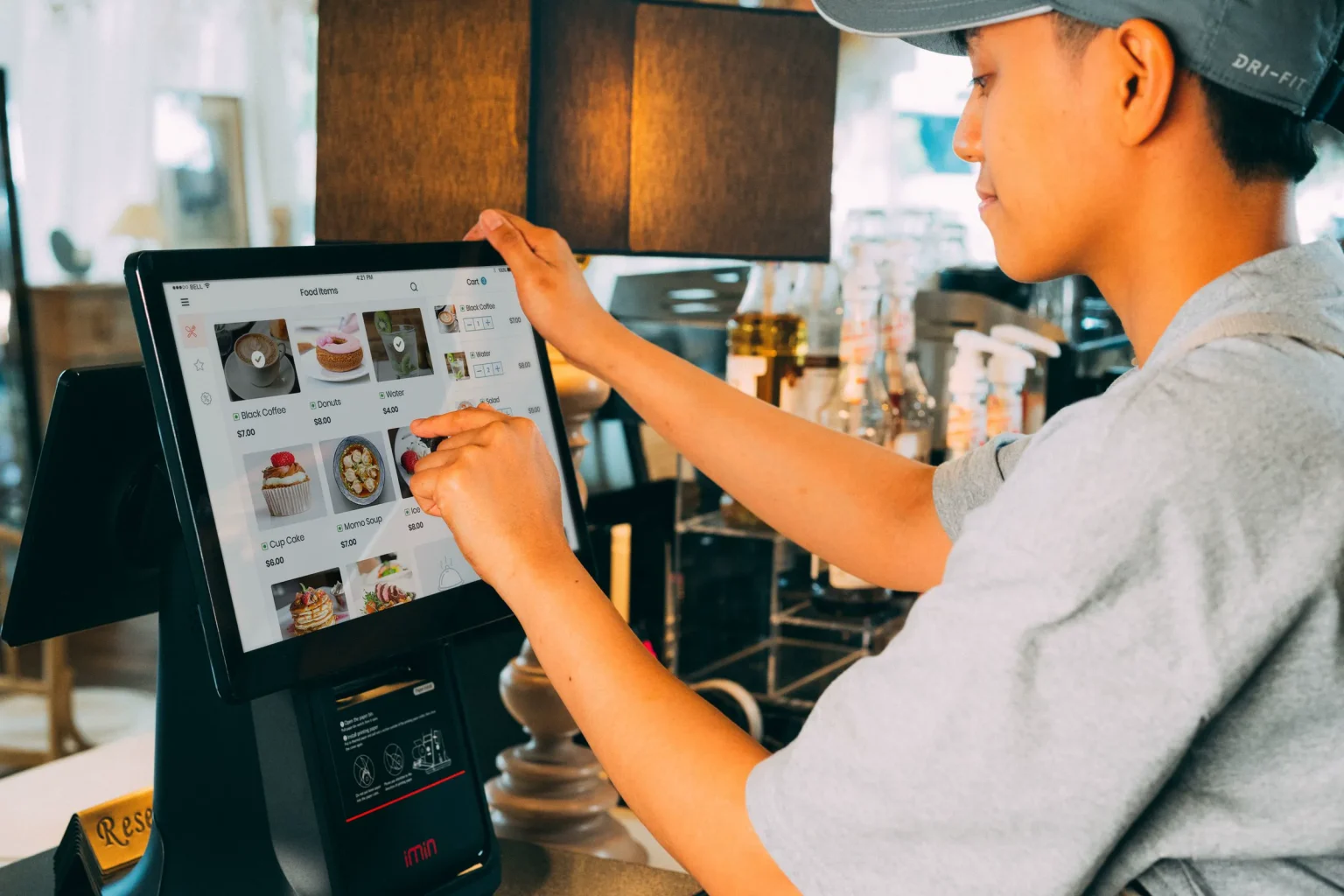 Funcionária de um café a usar um terminal POS com ecrã tátil