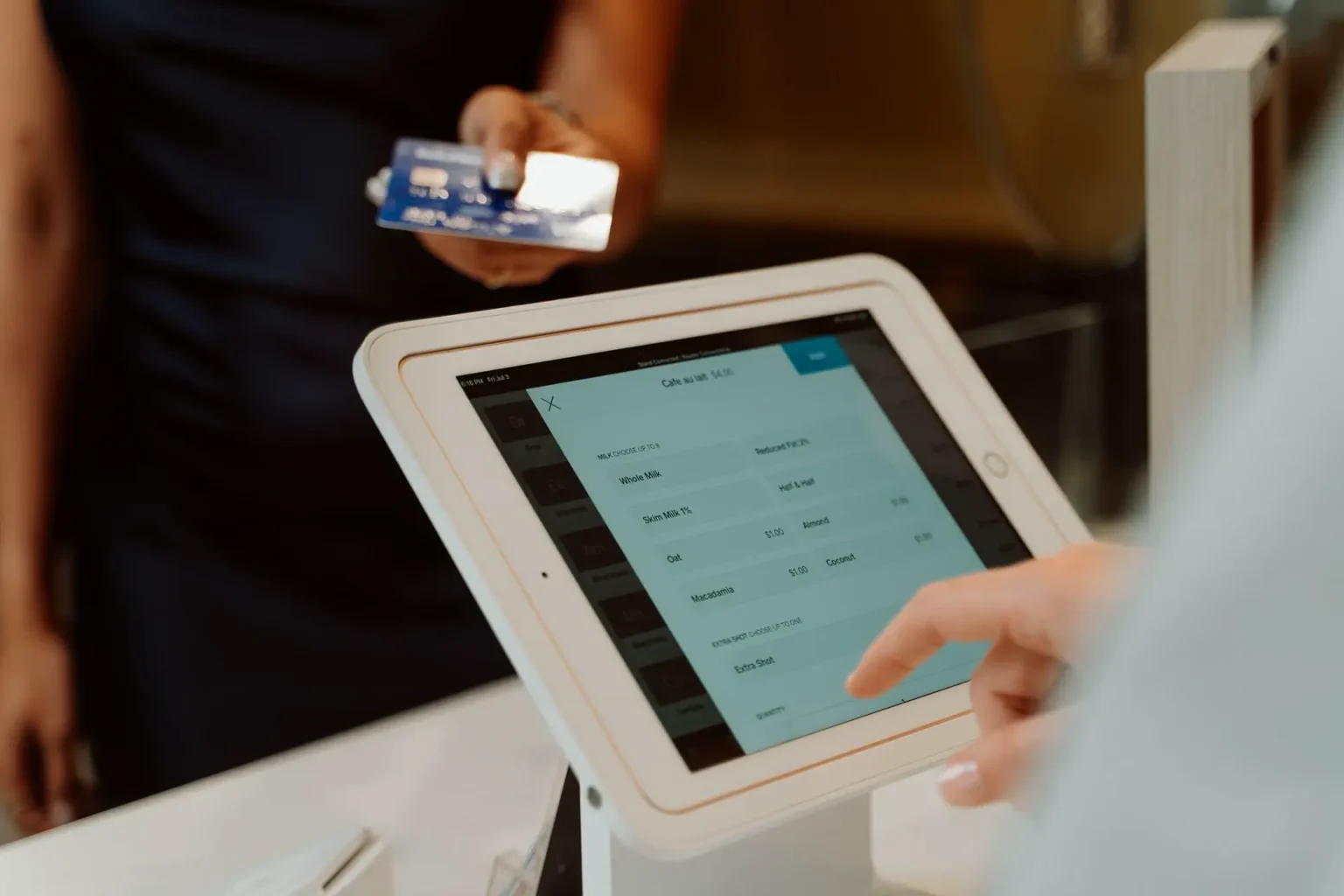 Terminal POS num suporte ao balcão, com um cliente a pagar com cartão